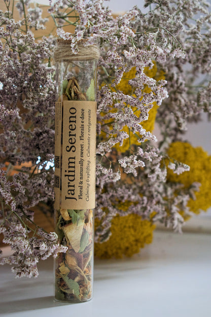 Jardim Sereno loose leaves tea in a glass tube on a floral background.