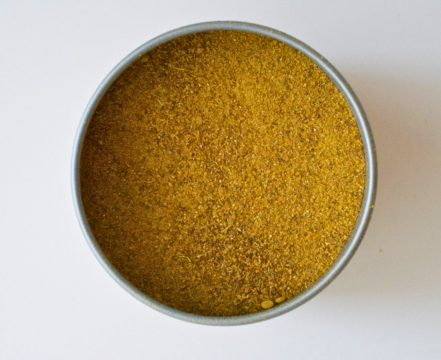 Metal container filled with a Pumpkin Spice mix powder on a white background