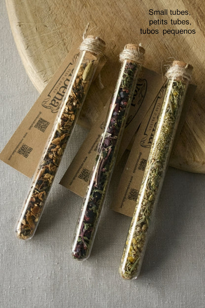 3 Small glass tubes on wooden board. All filled with different tea blends and have all a kraft label 