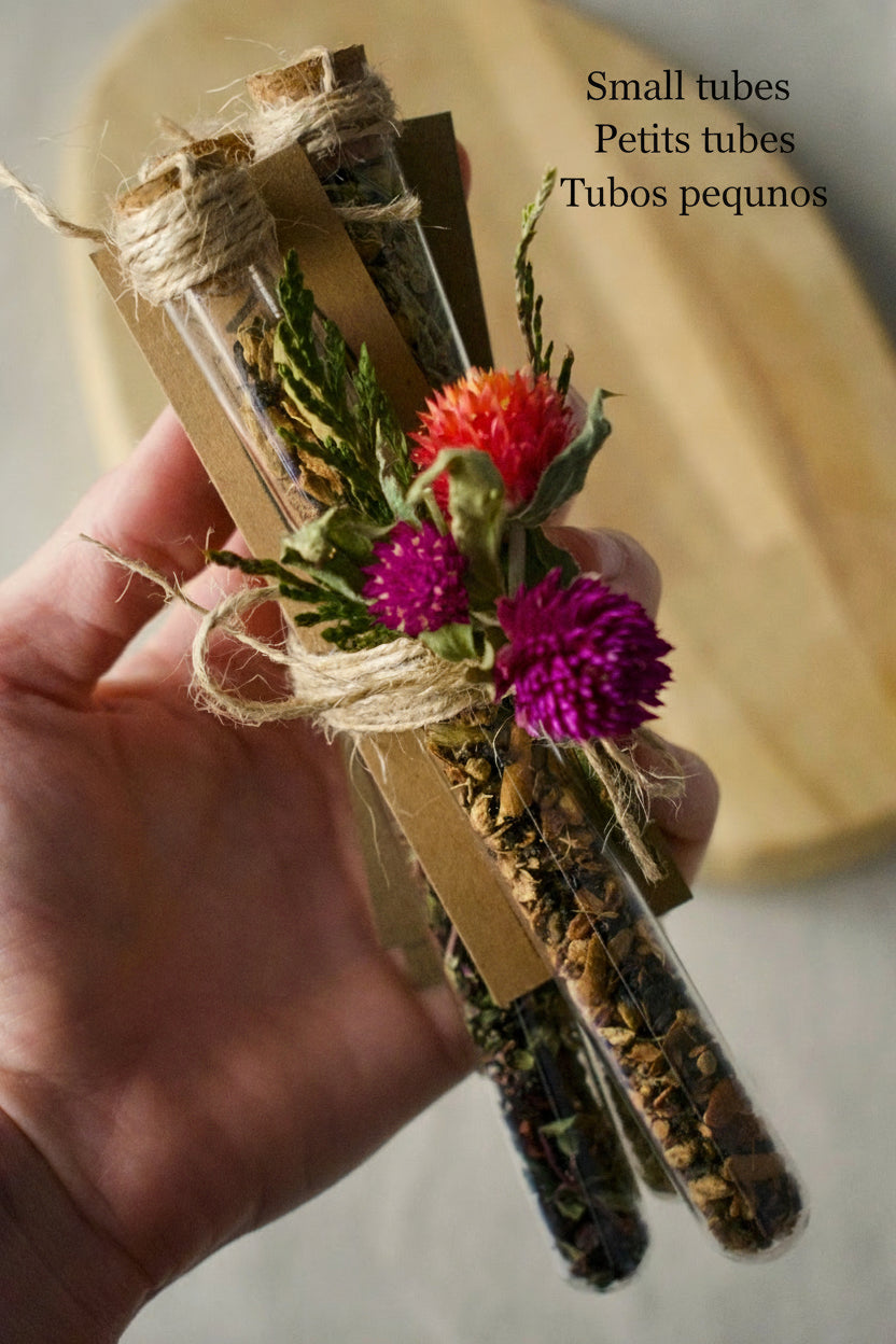 Bundle of three tubes held by a hand, tied together with a rope and some flowers. Background, wooden board and linen tablecloth.