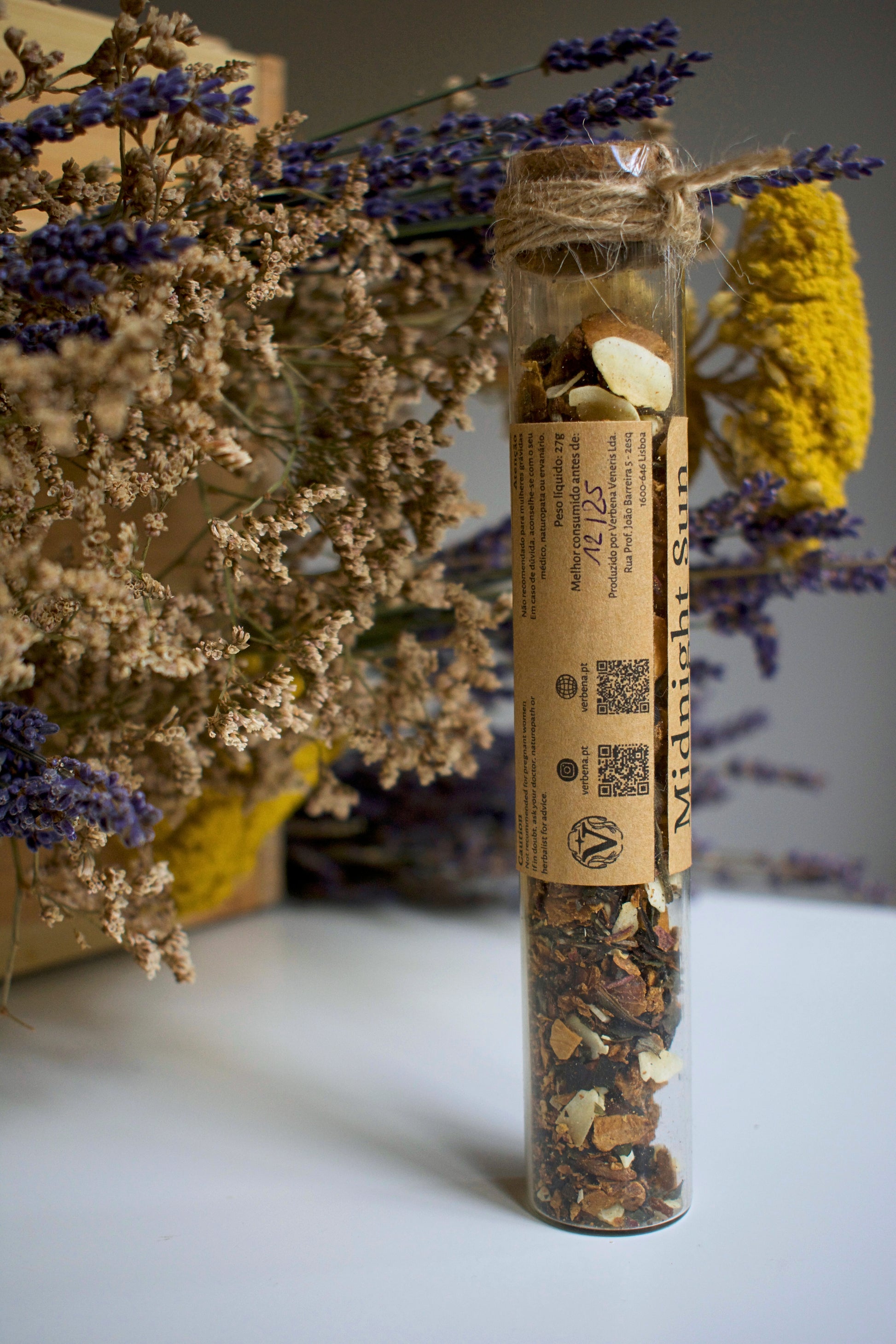 Herbal tea packaging labeled 'Midnight Sun' with dried herbs and flowers on a neutral background