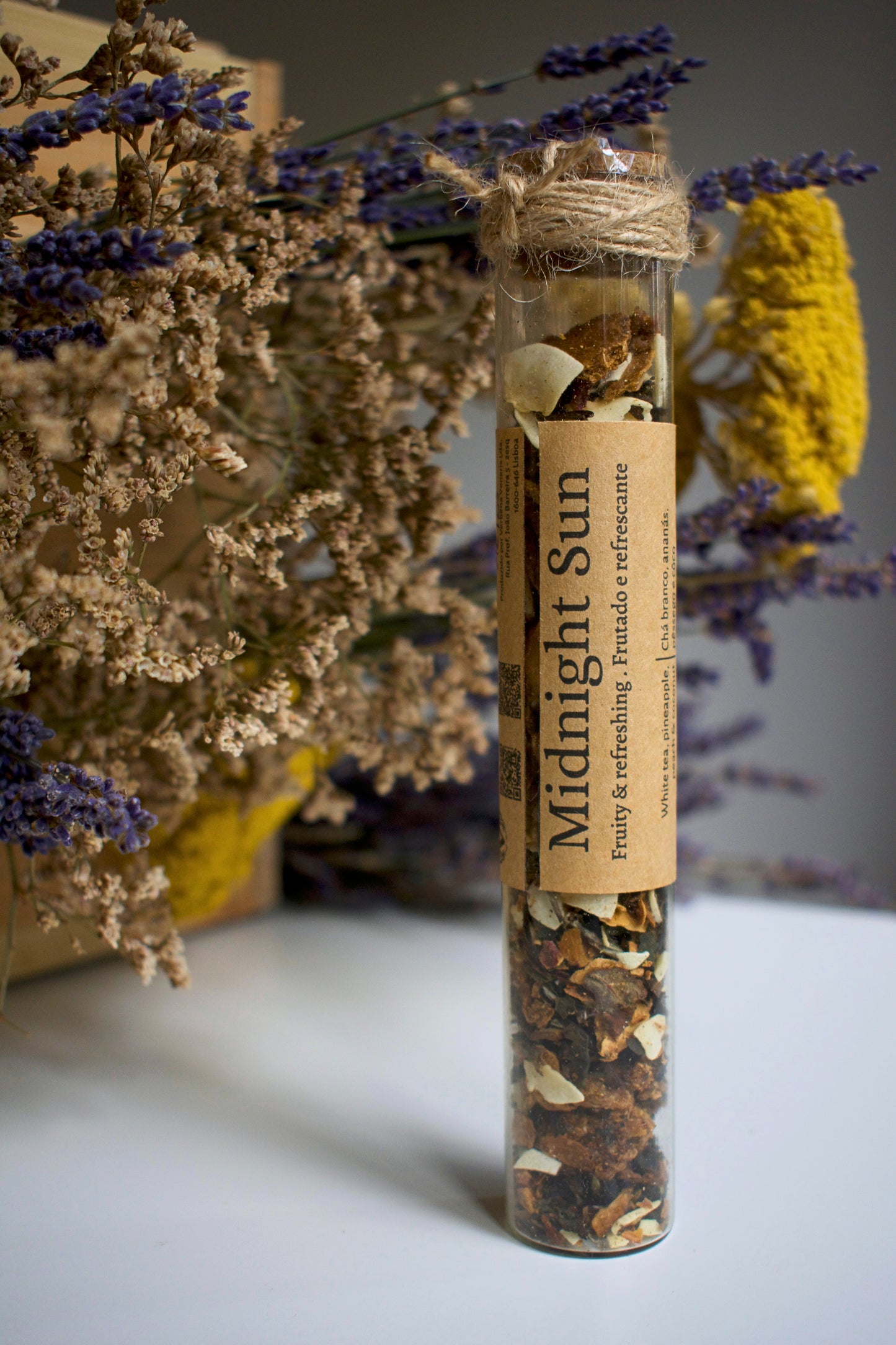 Herbal tea packaging labeled 'Midnight Sun' with dried herbs and flowers on a neutral background